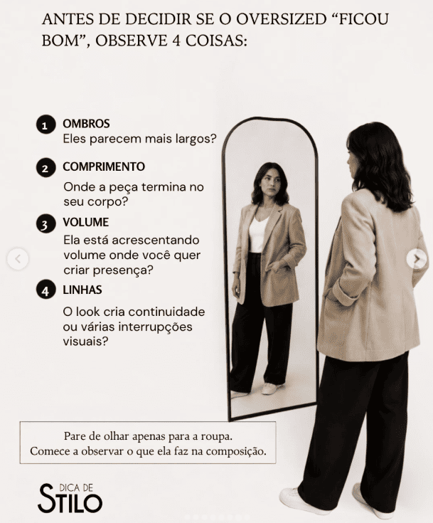 mulher diante do espelho observando ombros, comprimento, volume e linhas de um blazer oversized.